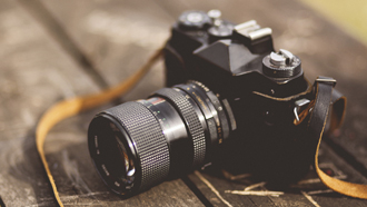 Máquina fotográfica pousada em cima de mesa de madeira para teste.